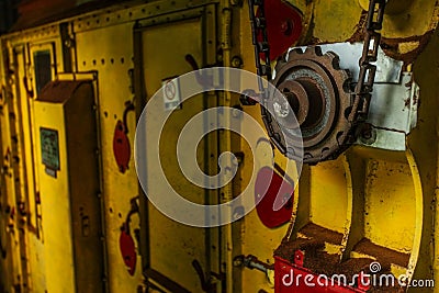 Old rusty cogwheel and chain on a yellow dryer machinery used in Stock Photo