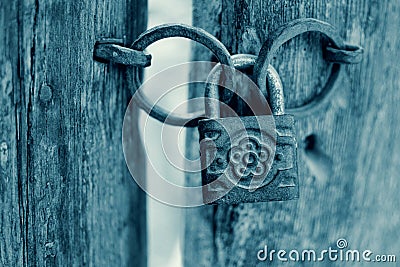 Old Rusty Decorated Padlock on a Wooden Door in Cyan. Stock Photo