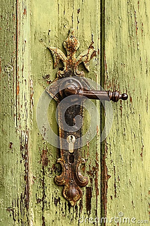 Old rusty door handle on green door. Detail of rustic old vintage and rusty grungy iron door handle installed on an ornament door Stock Photo