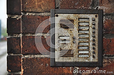 Old rusty intercom with buttons on a red brick wall of a building Stock Photo