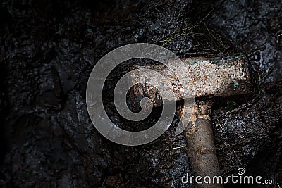 Old rusty iron construction hammer on the mud, dramatic photography and low key photography. construction tool and crime concept Stock Photo