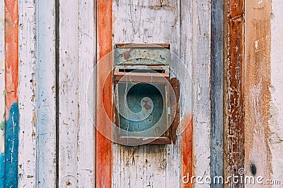 Old rusty mailbox on colour wooden door close up. Peeling paint door. Vintage rusty postbox or letterbox concept. Stock Photo