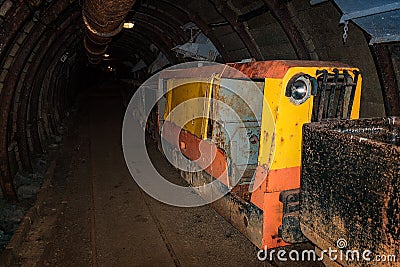 Old and rusty metal mine train with wagons in mine tunnel with wooden timbering Stock Photo