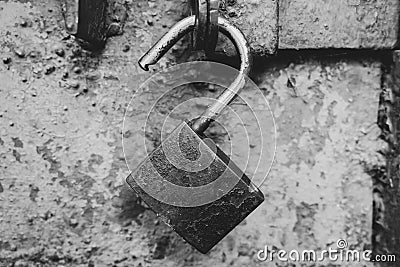 Old rusty padlock on door, monochrome. Open aged lock, black and white. Privacy and protection concept. Stock Photo