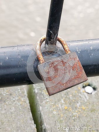 Old rusty padlock up close locked on black metal gate Stock Photo