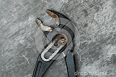 Old and rusty plumbing pliers on concrete floor Stock Photo