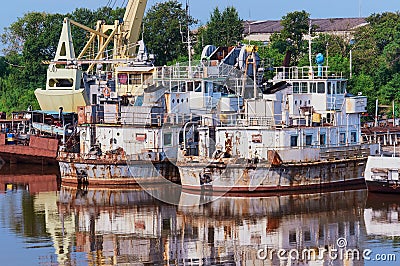 Old rusty river ships in the backwater in summer. Corrosion of metal. Reflection in water. The concept of recycling Stock Photo