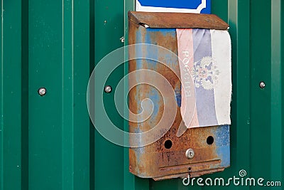 old rusty russian mailbox on the wall with extremely faded small fabric russian flag with with coat of arms Stock Photo