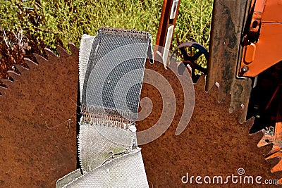 Old rusty saw blade mounted on an orange tractor front Stock Photo