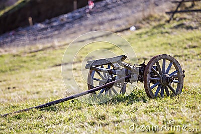 Old rusty vintage primitive wagon cart trailer with big wooden wheels on sunny grassy meadow background. Outdated rural Stock Photo