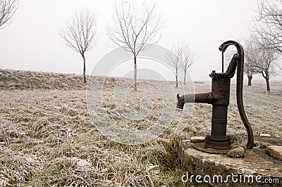 Old rusty water pump on the countryside in winter Stock Photo