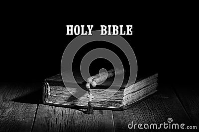 An old sacred book and a rosary on a wooden table Stock Photo