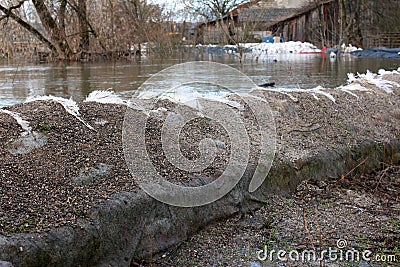 Old sandbags flood protection holding back river Stock Photo