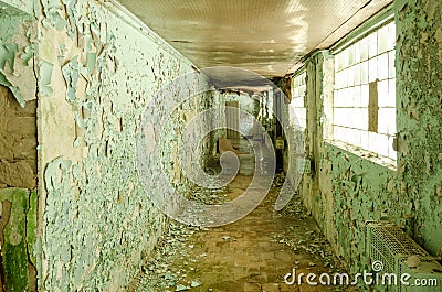 Old, scary hallway with green cracked paint, radiators and windows. Forgotten, abandoned ghost town Skrunda, Latvia. Former Soviet Stock Photo