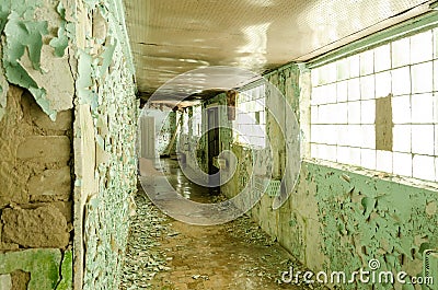 Old, scary hallway with green cracked paint, radiators and windows. Forgotten, abandoned ghost town Skrunda, Latvia. Former Soviet Stock Photo