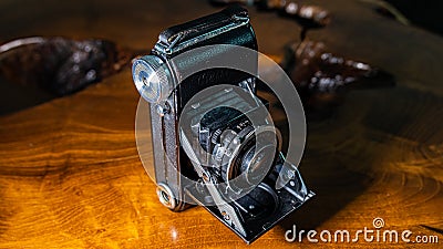 Old scratched and dusty antique photo camera, with foldable original Carl Zeiss Lens, on a rustic wooden table. Editorial Stock Photo