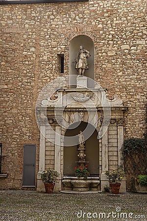 Old sculpture with small fountain and plants and flowers in pots Stock Photo