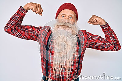 Old senior man with grey hair and long beard wearing hipster look with wool cap showing arms muscles smiling proud Stock Photo