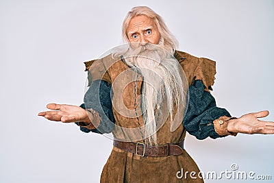 Old senior man with grey hair and long beard wearing viking traditional costume clueless and confused with open arms, no idea Stock Photo