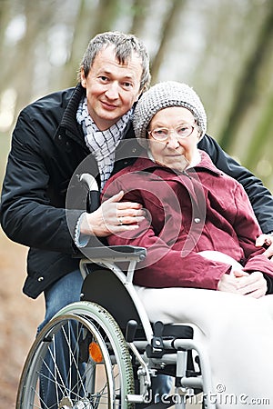 Old senior woman in wheelchair with careful son Stock Photo