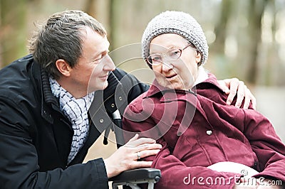 Old senior woman in wheelchair with careful son Stock Photo