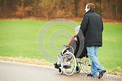 Old senior woman in wheelchair with careful son Stock Photo