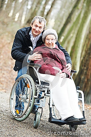 Old senior woman in wheelchair with careful son Stock Photo