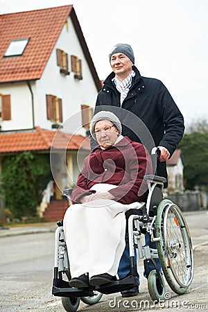 Old senior woman in wheelchair with careful son Stock Photo