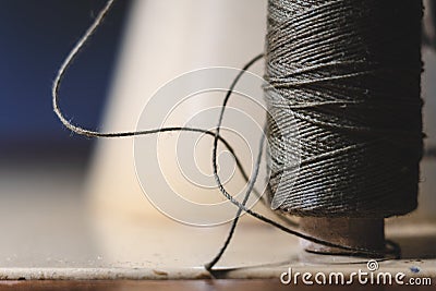 Old sewing machine needle with black thread, on a old grungy work table. Tailor`s work table. textile or fine cloth making. indust Stock Photo