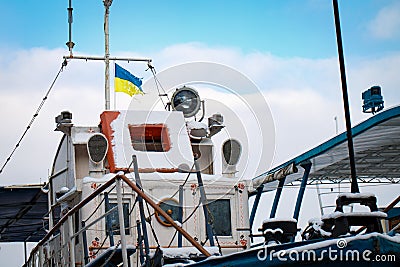 Old shabby flag of Ukraine waving over a ship against a blue sky Stock Photo