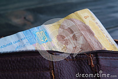 Old shabby leather wallet with Ukrainian hrivna bill on wooden t Stock Photo