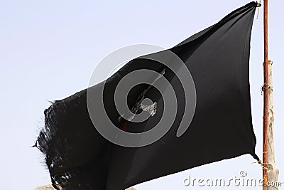 An old shabby pirate flag is developing in the sky Stock Photo