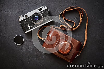 Old shabby retro camera and leather carrying case on black graphite background in close-up, flat lay Stock Photo