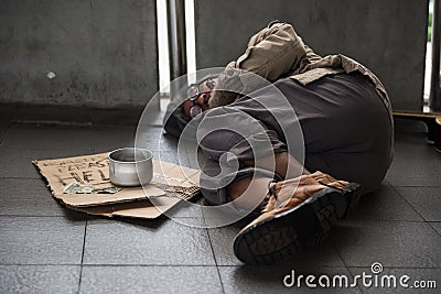 Old sick beggar or Homeless dirty man sleep on footpath with donate bowl, dollar bill, coin, paper cardboard with help text. Stock Photo