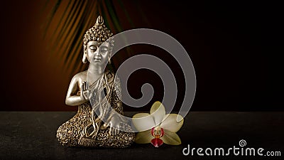 Old silver color statuette Buddha sitting in meditation pose with orhid flower Stock Photo