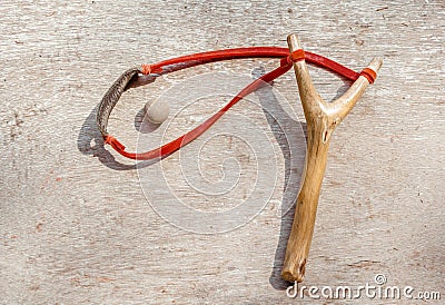 The old slingshot and clay pellet on old wood background. Stock Photo