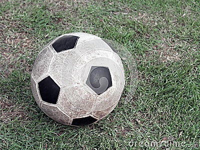 old dirty stained soccer ball made of synthetic rubber on green grass field Stock Photo