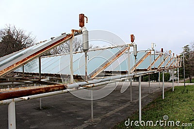 Old solar panels on abandoned parking lot with rusted pipes and metal support Stock Photo
