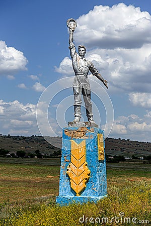 The old Soviet sculpture Worker and Collective Farm on road offers entry into a dying Ukrainian village. Old Soviet monument, Editorial Stock Photo