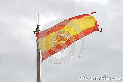 Old Spanish flag on a pole, undulating in the wind with clouds at the background, Santa Barbara castle of Alicante Stock Photo