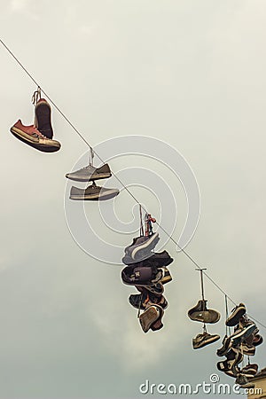 Old sports shoes hanging from the wire Editorial Stock Photo