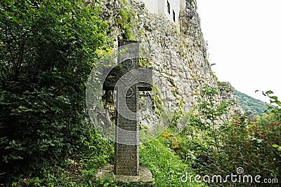 Old srone croos against Bran Castle in Romania. Dracula medieval castle in Carpathians, Transylvania Stock Photo