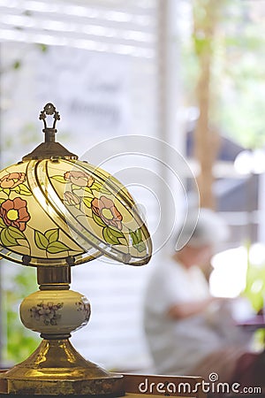 The Old Stained Glass Tiffany table Lamp with blurred vertical background of Vintage coffee shop Stock Photo