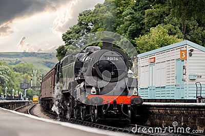 Old steam train in train station with chimney working to carry passengers Editorial Stock Photo