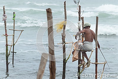 Old stilt fisherman with his wooden rod facing back to camera angel, fishing in a traditional unique method in Sri Lanka Editorial Stock Photo