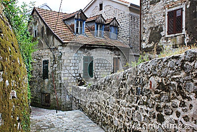 an old stone ancient European city street, ends with a small house with green shutters, a red tiled roof Stock Photo