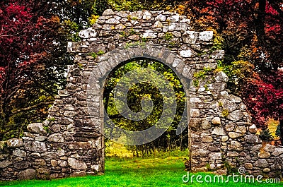 Old stone entrance wall in the garden with colorful foliage Stock Photo