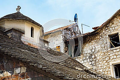 Old stone house in a poor neighborhood, standing next to a small ancient church. Stock Photo