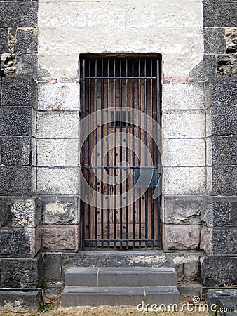 Old stone jail wooden door with iron bars Stock Photo