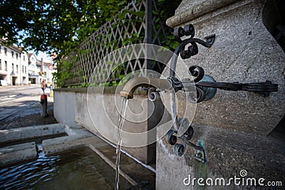 Old stone and metal public drinking water fountain in a city in Switzerland, Europe. Daytime, wide angle, no peop Stock Photo